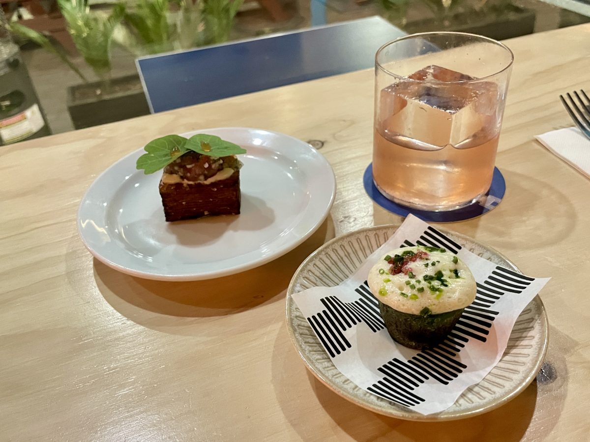 Two plates with small dishes and a glass with a half-drunk cocktail. 