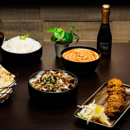 A range of dishes on a table with a small bottle of wine