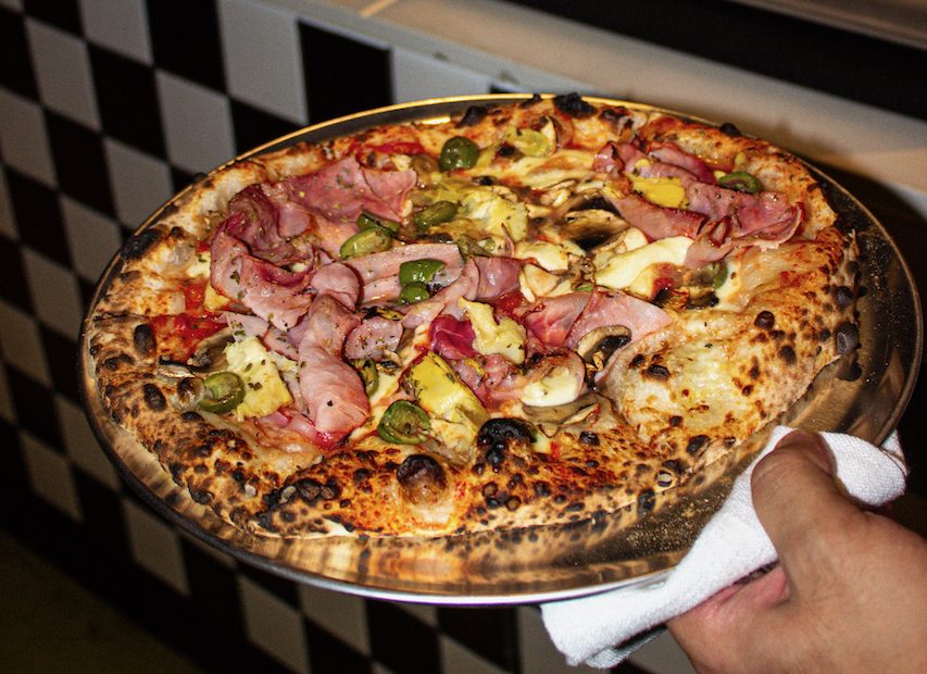 A delicious looking pizza topped with ham, olives and cheese.