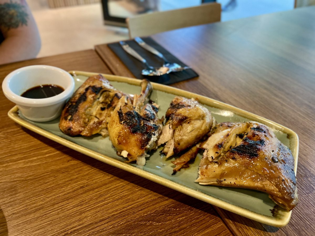 A plate with four pieces of grilled, charred chicken.