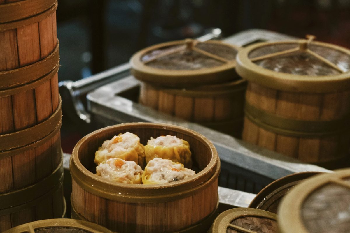 A steamer basket of siu mai dumplings among other steamer baskets with lids closed. 