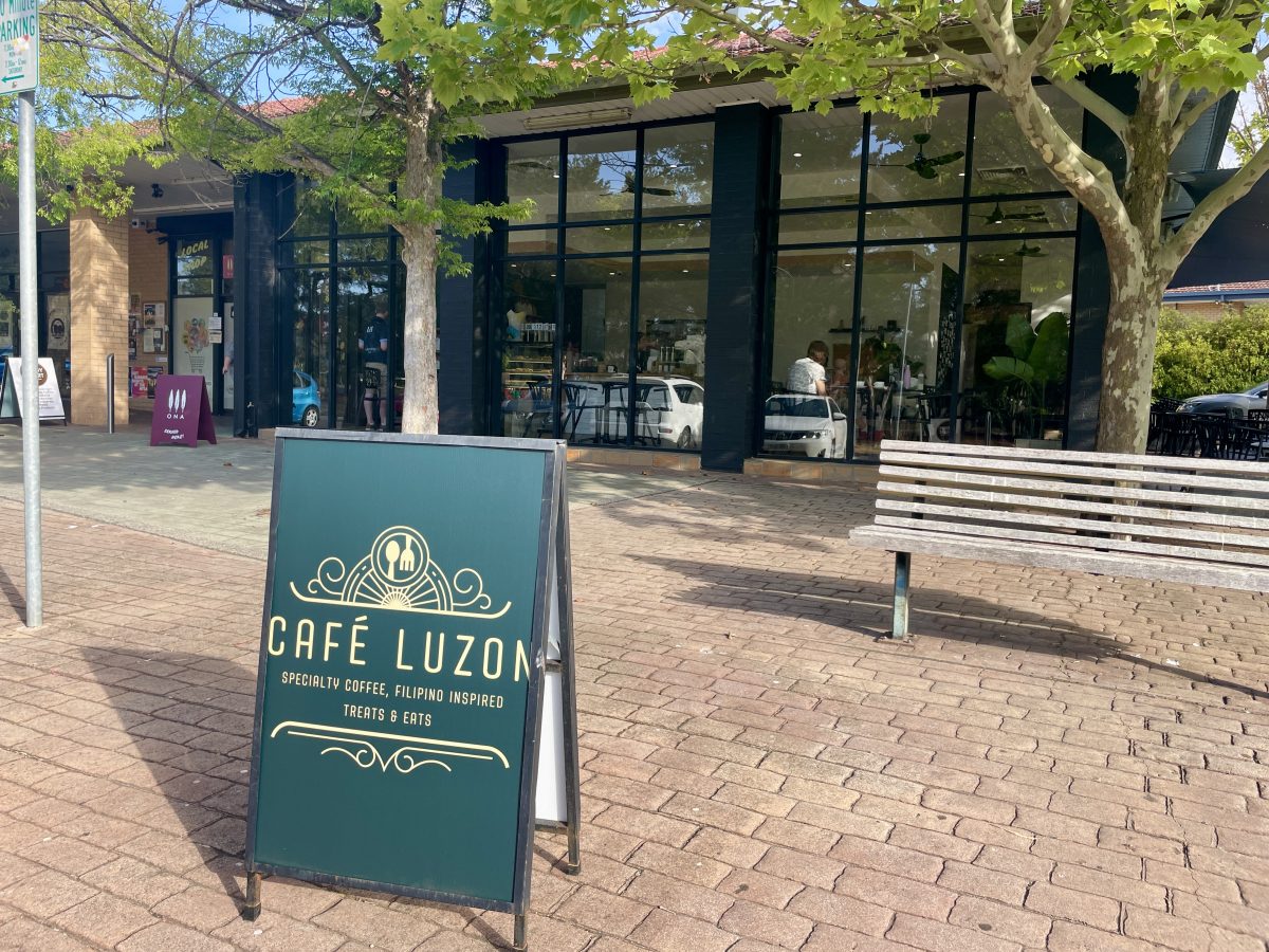An A-fram sign reading 'Cafe Luzon: Specialty coffee and Filipino inspired treats and eats