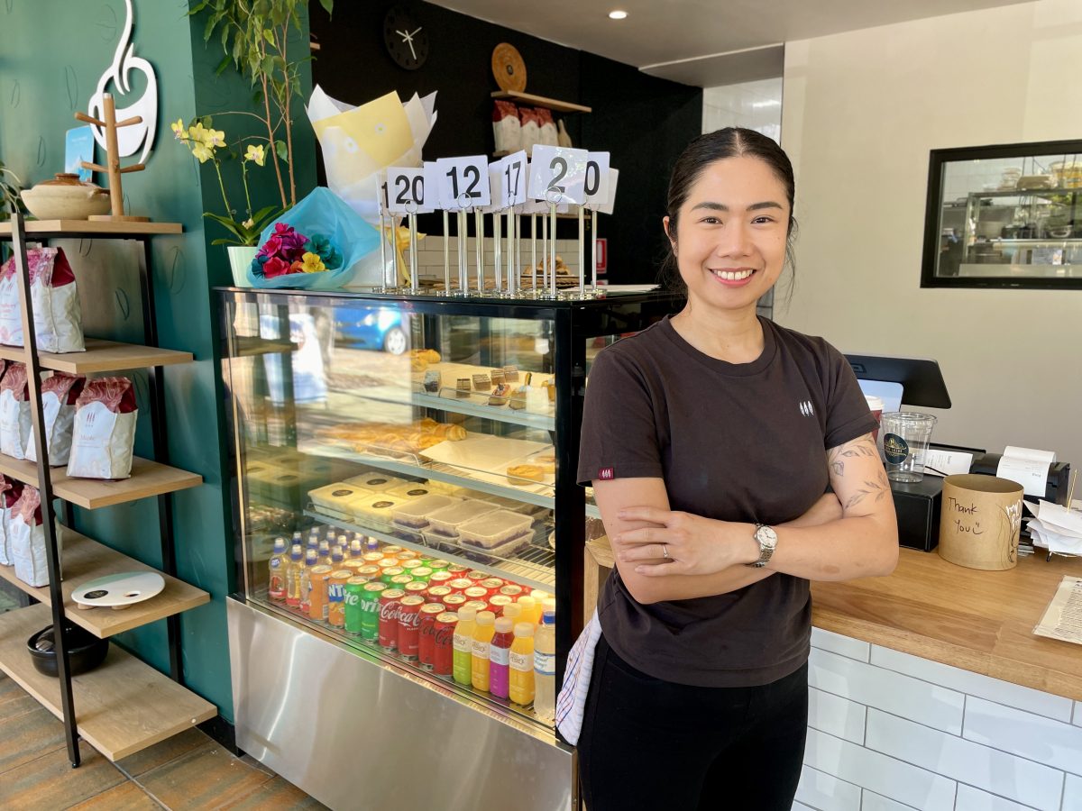 A young woman stands in front of a cafe counter