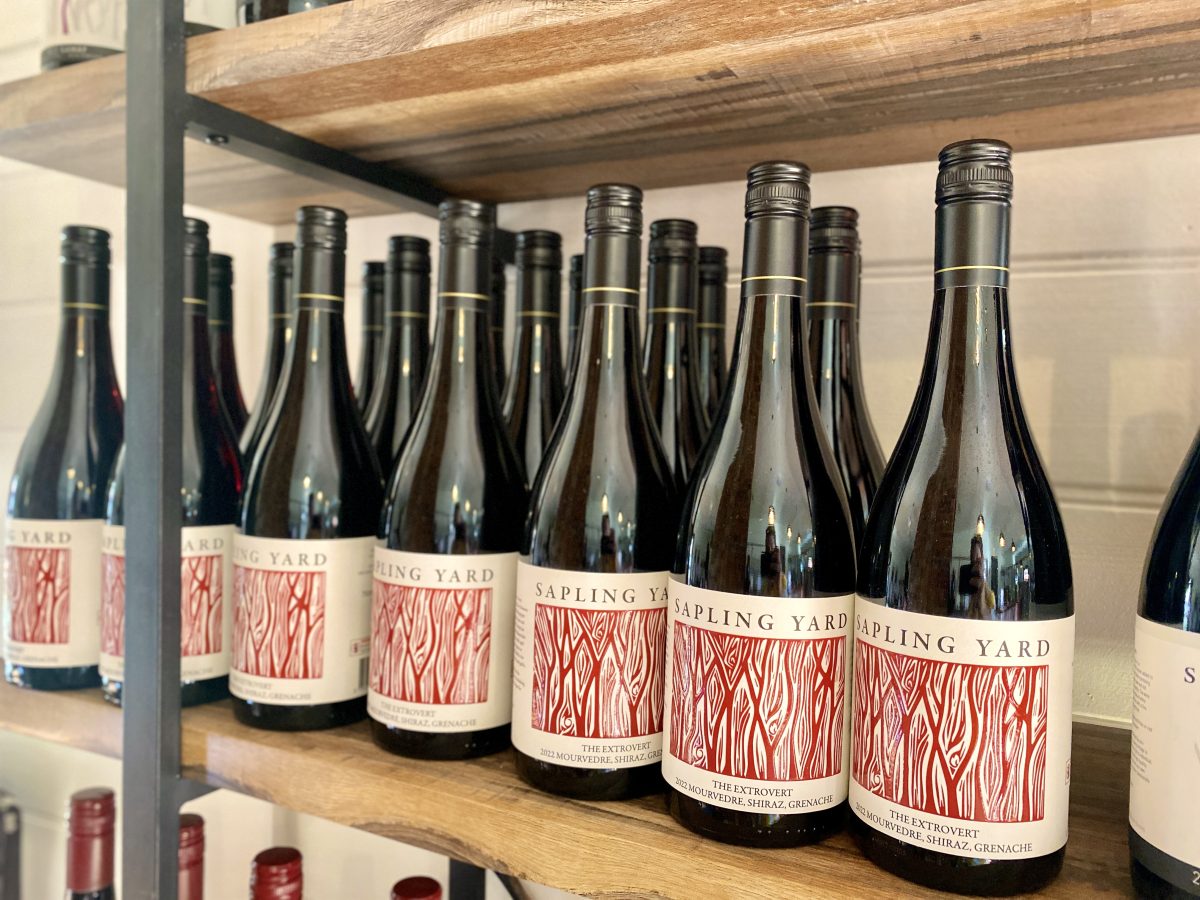 Bottles of red wine on a shelf with red and white Sapling Yard label.