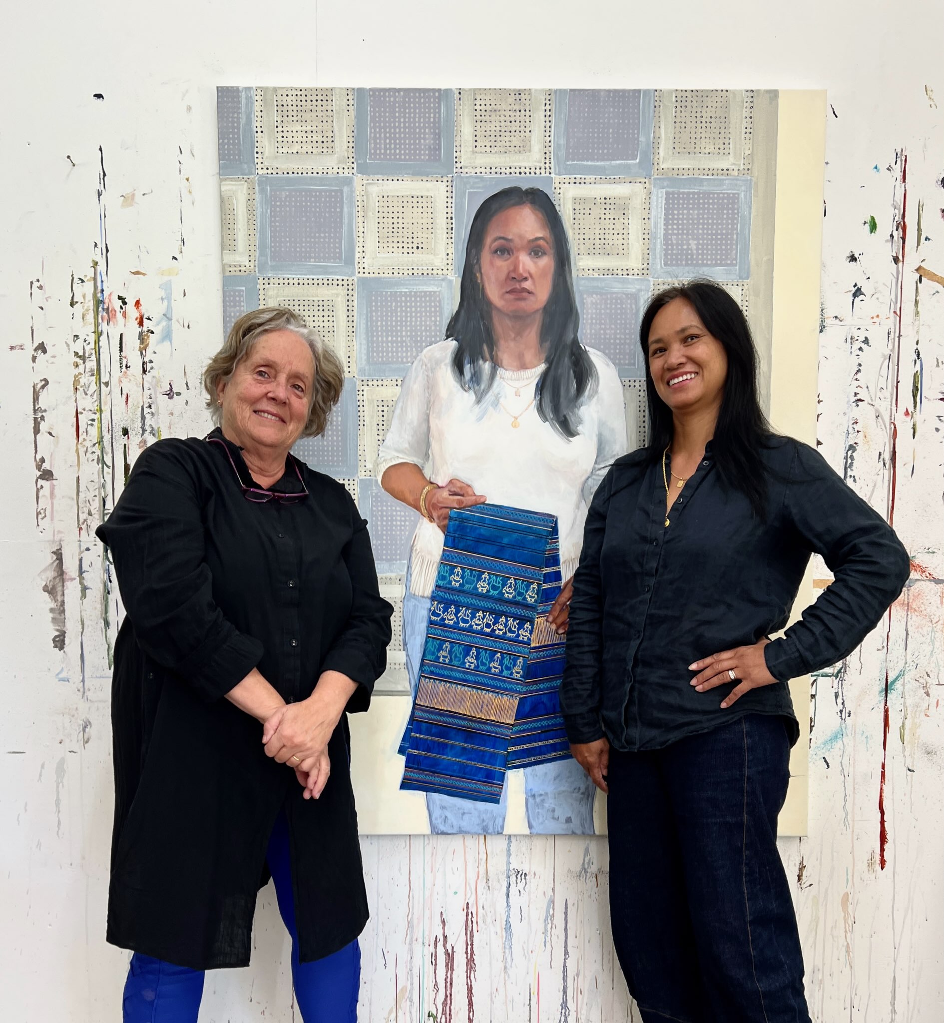Two women standing in front of a portrait