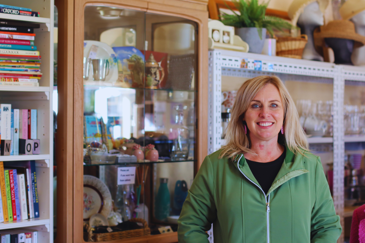 Woman stands in front of cabinets in an op shop