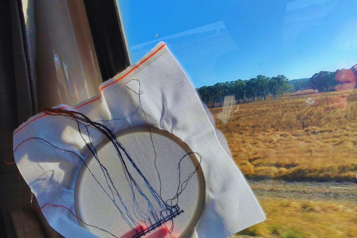 Cross-stitch frame being held against a train's window