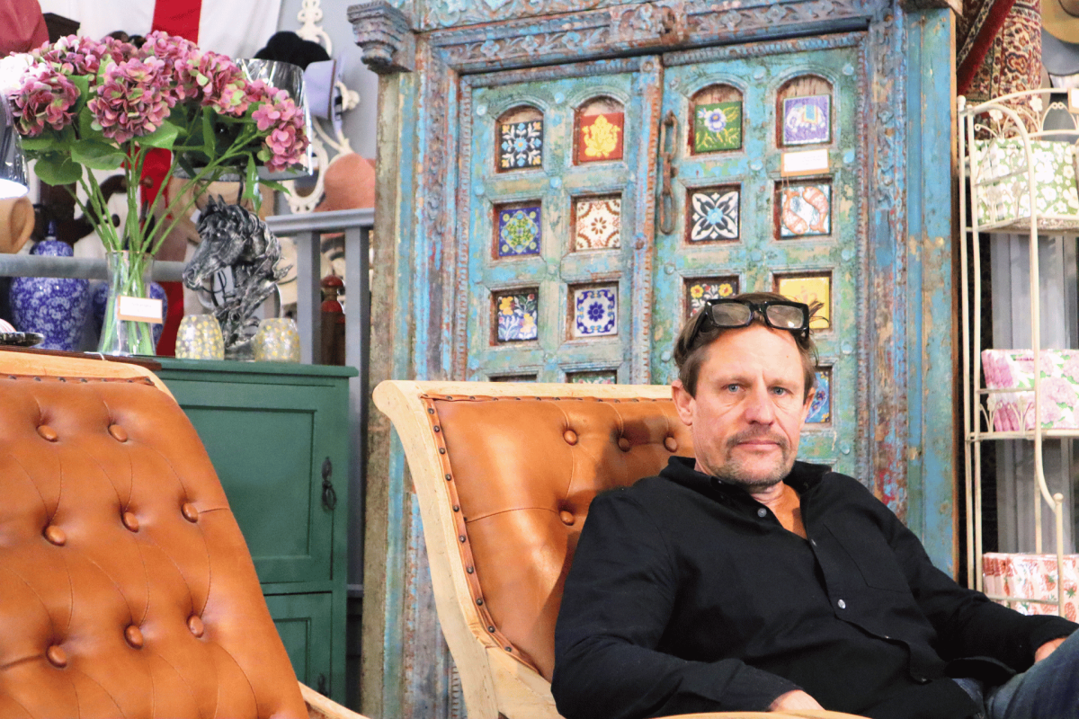 Man sits in chair in front of ornate door